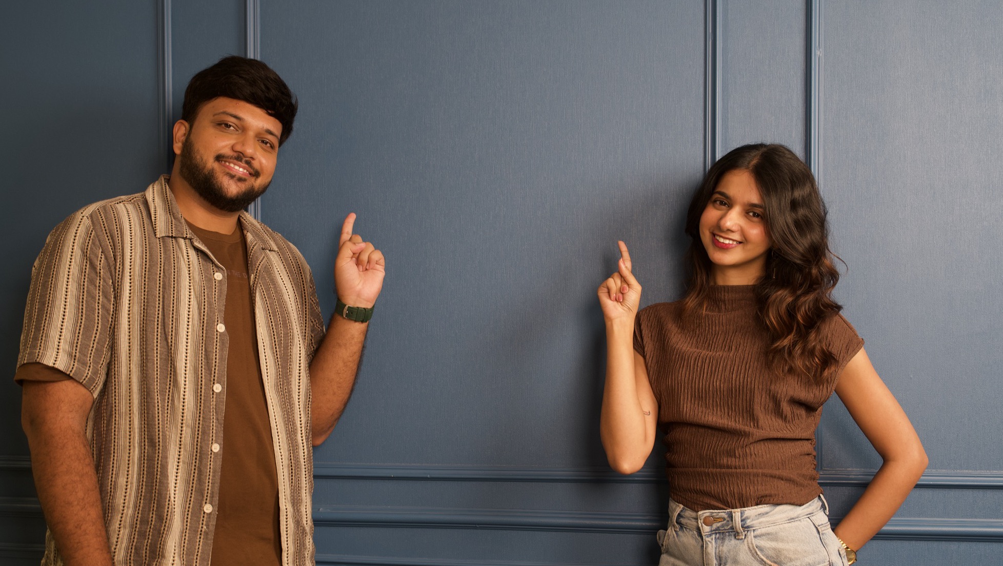 Shantanu Mohile and Ushma Asher smiling and pointing up at the wall between them